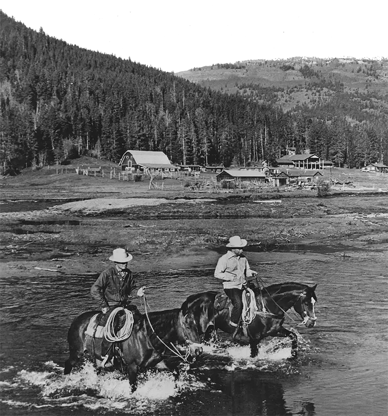 Bob Hide, a long-time wrangler who worked at the ranch through the 1950’s, riding across Willow Creek with a guest.
