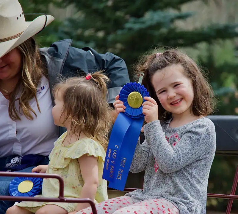 A little girl smiles as she shows off her blue ribbon from the Shodeo