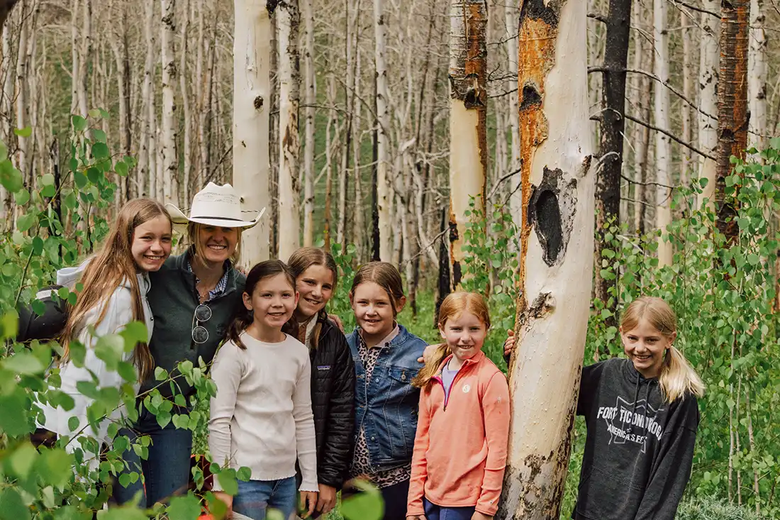 A counselor poses in the woods with her group of pre-teens